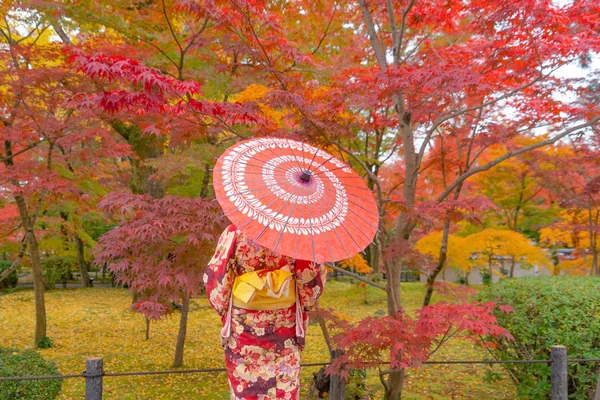 An Asian woman wearing Japanese traditional kimono with red umbr