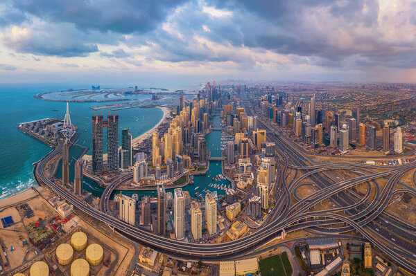 Aerial view of Dubai Marina and highways, Downtown skyline, United Arab Emirates or UAE. Financial district and business area in smart urban city. Skyscraper and high-rise buildings at sunset.