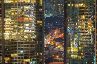 Ofis binalarının pencereleri geceleri aydınlatılır. Kentsel şehirde yansıması ile Cam mimarisi cephe tasarımı ile Aydınlatma, Finans bölgesinde Downtown Singapore City.