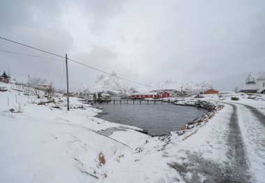 Ev, kulübe ya da ev, Reine City, Lofoten adalarındaki Norveç balıkçı köyü, Nordland, Norveç, Avrupa. Beyaz karlı dağ tepeleri, kış mevsiminde doğa manzarası.