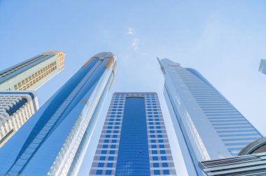 Yüksek binalara, gökdelenlere, mavi gökyüzü olan finans bölgesindeki mimarilere bakıyorum. Şehir merkezi Dubai, BAE 'de iş ve teknoloji konsepti için akıllı şehir..