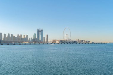Dubai Şehir Merkezi 'nin ufuk çizgisi, deniz sahilinde dalgalar, Birleşik Arap Emirlikleri ya da BAE. Seyahat tatili konseptinde finans bölgesi. Şehir merkezi. Gökdelenler, günbatımı gökyüzü.
