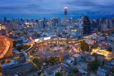 Meşgul sokak yollarında trafik ışığı olan Zafer Anıtı 'nın havadan görünüşü. Bangkok şehir merkezindeki Skyline kavşağında. Tayland. Akıllı şehir merkezindeki finans merkezi. Geceleri gökdelenler.
