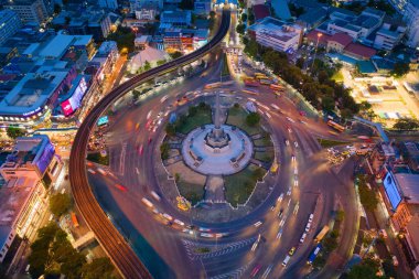 Meşgul sokak yollarında trafik ışığı olan Zafer Anıtı 'nın havadan görünüşü. Bangkok şehir merkezindeki Skyline kavşağında. Tayland. Akıllı şehir merkezindeki finans merkezi. Geceleri gökdelenler.