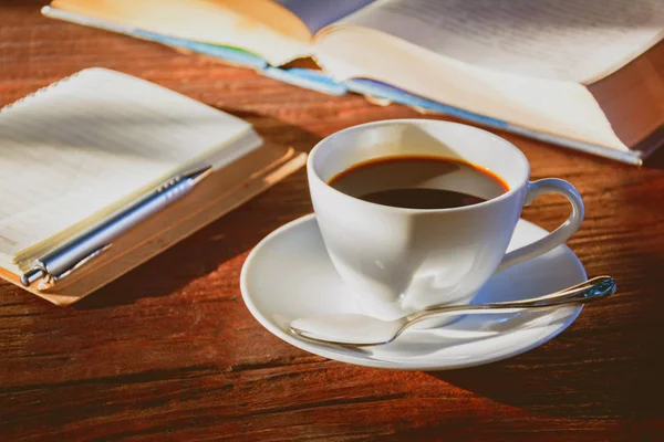 Kaffeebecher und Buch auf altem Holztisch — Stockfoto