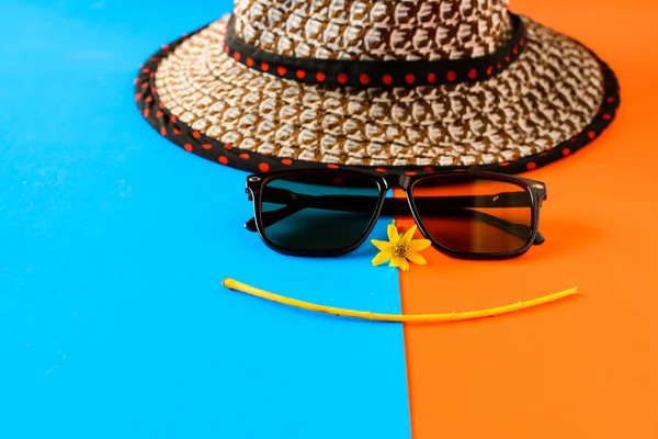 Güneş gözlüğü ve şapka mavi ve turuncu renkli kağıt üzerinde — Stok fotoğraf