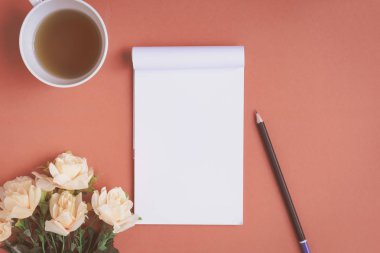 Düz yatıyordu defter ve gül kırmızı bir masa üzerine yerleştirilen