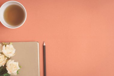 Düz yatıyordu defter ve gül kırmızı bir masa üzerine yerleştirilen