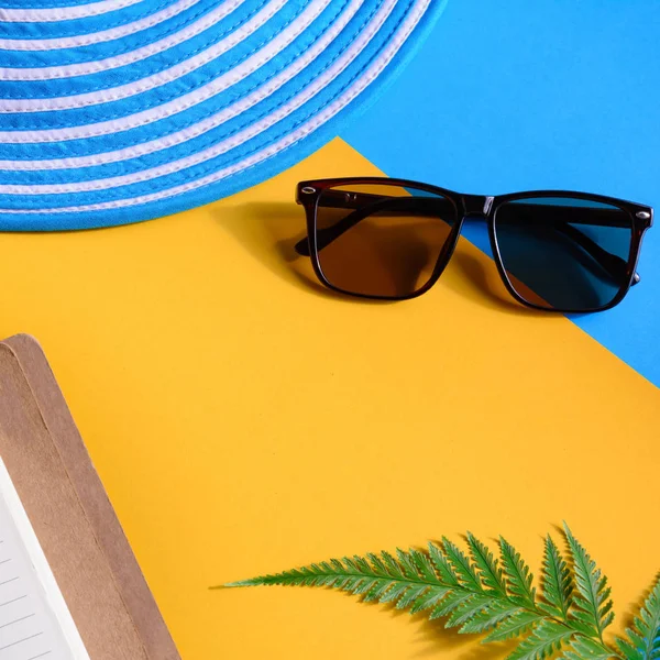Blauwe hoed en zonnebril op kleurrijke papier — Stockfoto