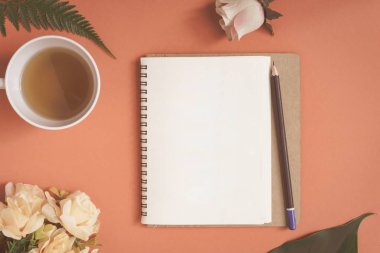 Düz yatıyordu defter ve gül kırmızı bir masa üzerine yerleştirilen