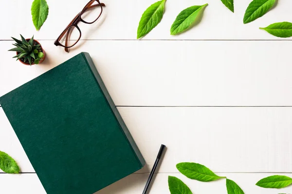 Plano poner gafas de libro y pluma sobre un fondo de madera blanca —  Fotos de Stock