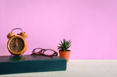 Kitaplar ve gözlük bir beyaz tahta masada saatler ve decorat vardır