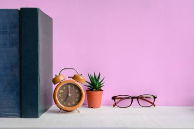 Kitaplar ve gözlük bir beyaz tahta masada saatler ve decorat vardır