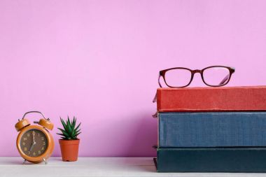 Kitaplar ve gözlük bir beyaz tahta masada saatler ve decorat vardır