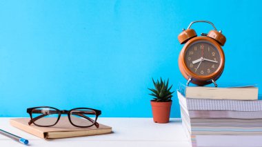 Kitaplar ve gözlük bir beyaz tahta masada saatler ve decorat vardır