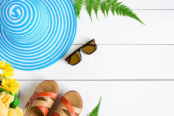 Mavi şapka güneş gözlüğü ve ayakkabı Beyaz ahşap masa üzerinde
