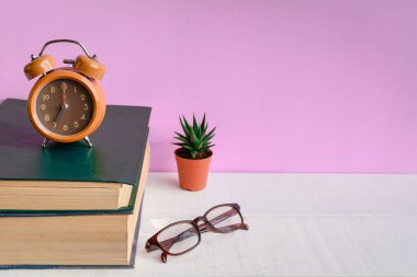 Kitaplar ve gözlük bir beyaz tahta masada saatler ve decorat vardır