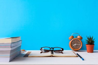 Kitaplar ve gözlük bir beyaz tahta masada saatler ve decorat vardır