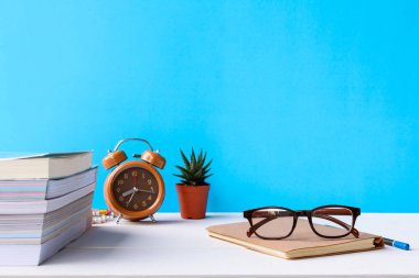 Kitaplar ve gözlük bir beyaz tahta masada saatler ve decorat vardır