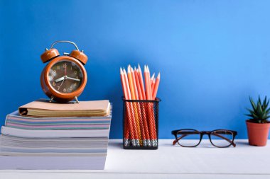 Kitap kalem ve Beyaz ahşap bir masa üzerinde gözlük vardır saatleri ve 