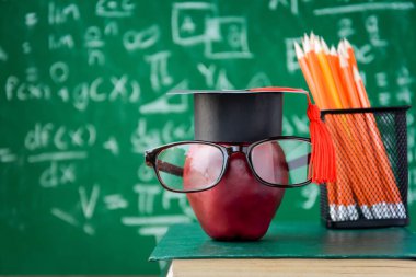 Elma bilgi sembolü ve masanın üstüne kalem kitap