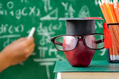 Elma bilgi sembolü ve masanın üstüne kalem kitap