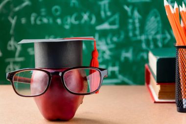 Elma bilgi sembolü ve masanın üstüne kalem kitap