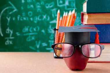 Elma bilgi sembolü ve masanın üstüne kalem kitap