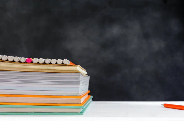 Könyv és a ceruza a fehér asztal fekete tábla háttér tanulmány — Stock Fotó