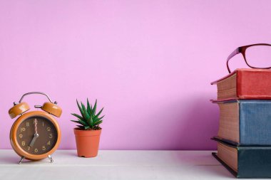 Kitaplar ve gözlük bir beyaz tahta masada saatler ve decorat vardır