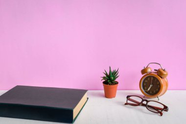 Kitaplar ve gözlük bir beyaz tahta masada saatler ve decorat vardır