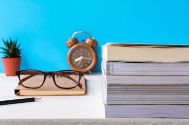 Kitaplar ve gözlük bir beyaz tahta masada saatler ve decorat vardır