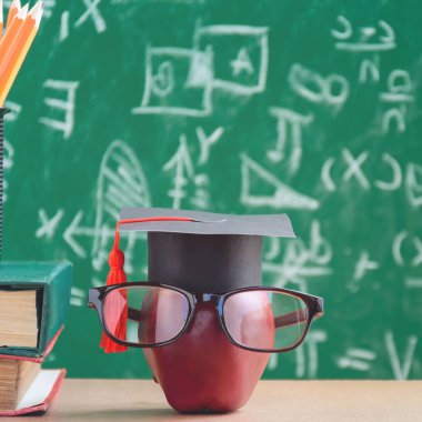 Elma bilgi sembolü ve masanın üstüne kalem kitap