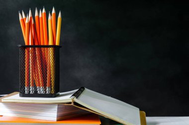 çalışma kitabı ve beyaz masa kara tahta zemin üzerine kalem