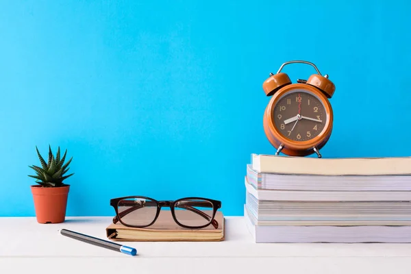 Libros y vasos en una mesa de madera blanca son relojes y decoración — Foto de Stock