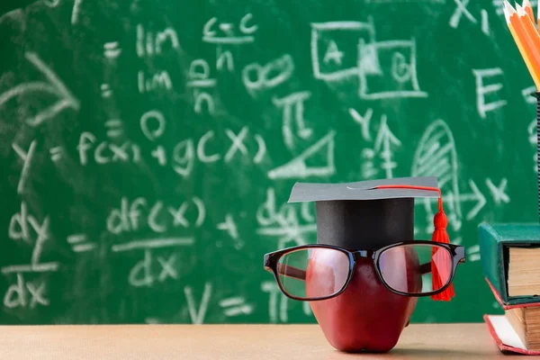 Elma bilgi sembolü ve masanın üstüne kalem kitap