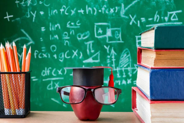 Elma bilgi sembolü ve masanın üstüne kalem kitap