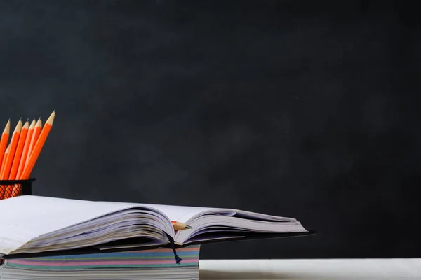 Libro y lápiz sobre fondo de tablero negro de mesa blanca — Foto de Stock