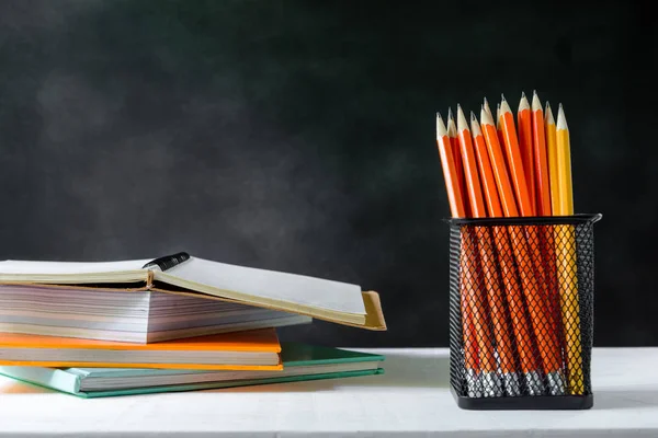 çalışma kitabı ve beyaz masa kara tahta zemin üzerine kalem