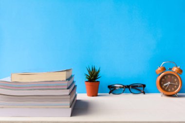 Kitaplar ve gözlük bir beyaz tahta masada saatler ve decorat vardır