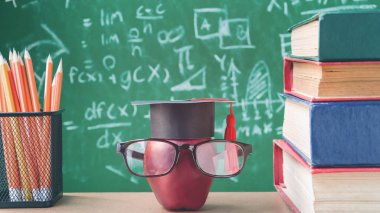 Elma bilgi sembolü ve masanın üstüne kalem kitap