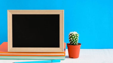 Ahşap masa üzerinde çerçeve ve kitap kalem kadar sahte ile yazı tahtası