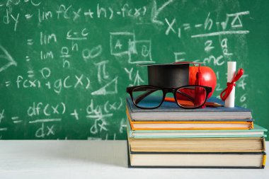 Elma bilgi sembolü ve masanın üstüne kalem kitap