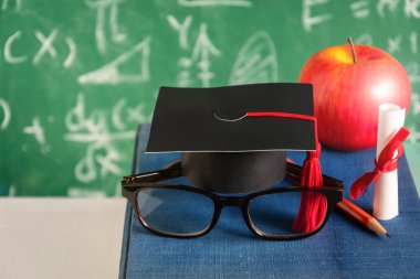 Elma bilgi sembolü ve masanın üstüne kalem kitap