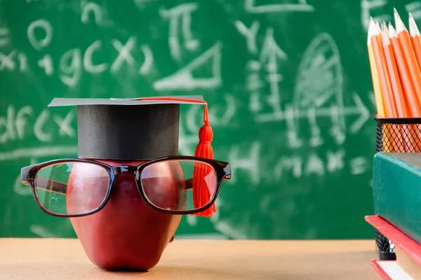 Elma bilgi sembolü ve masanın üstüne kalem kitap