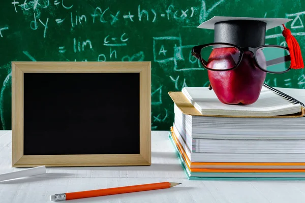 Elma bilgi sembolü ve masanın üstüne kalem kitap 