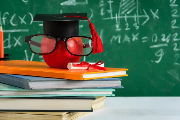 Elma bilgi sembolü ve masanın üstüne kalem kitap