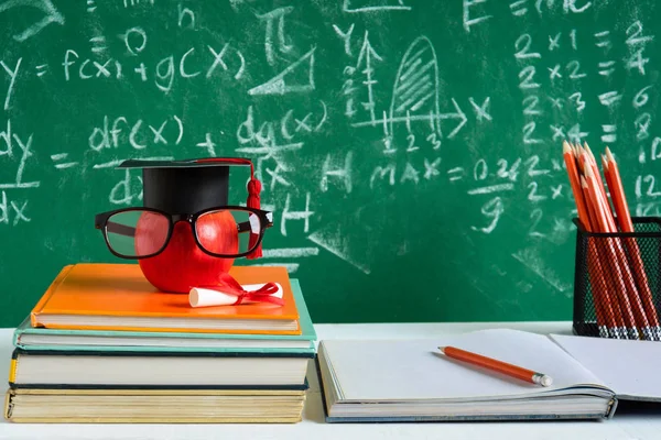 Elma bilgi sembolü ve masanın üstüne kalem kitap