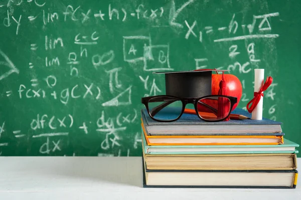 Elma bilgi sembolü ve masanın üstüne kalem kitap