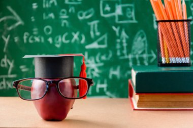 Elma bilgi sembolü ve masanın üstüne kalem kitap